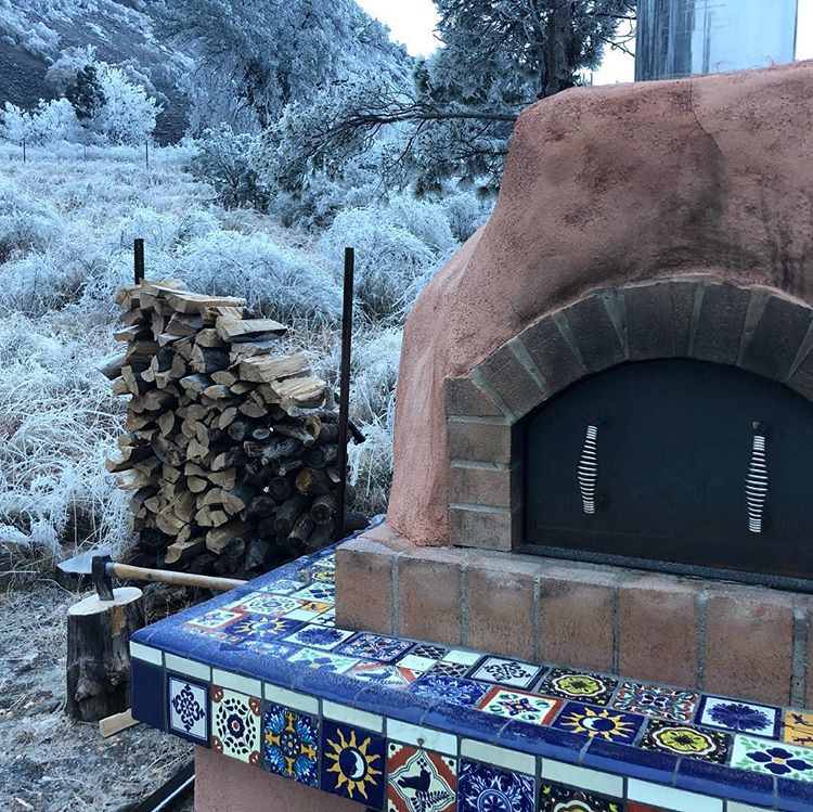 Wood Fired Oven Outside Near Stack of Wood