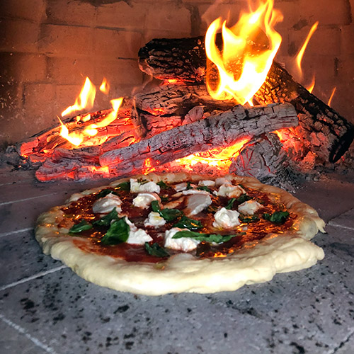 Wood Fired Pizza in Oven Near Flames